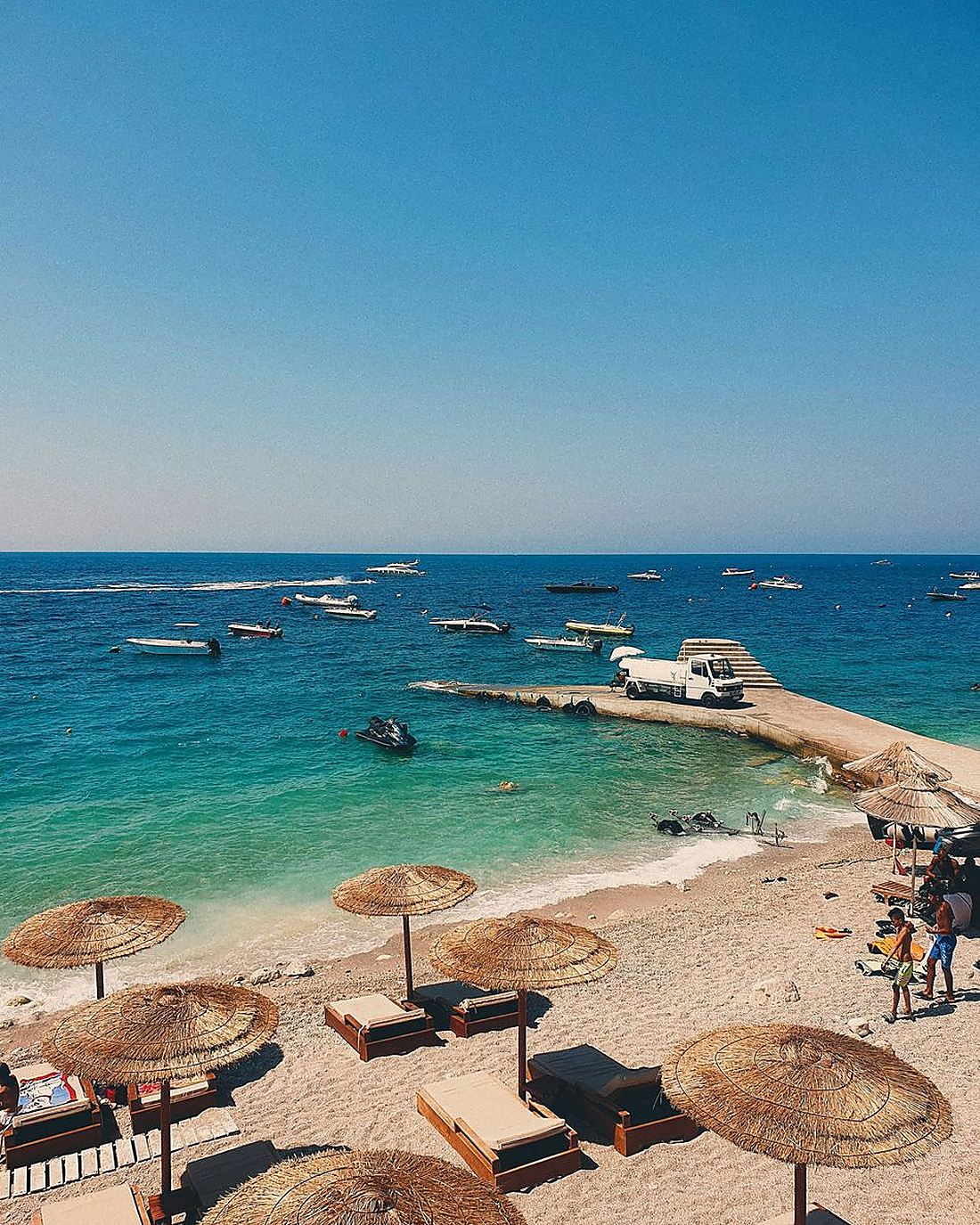 Strand med stråparasoller ved den albanske rivieraen
