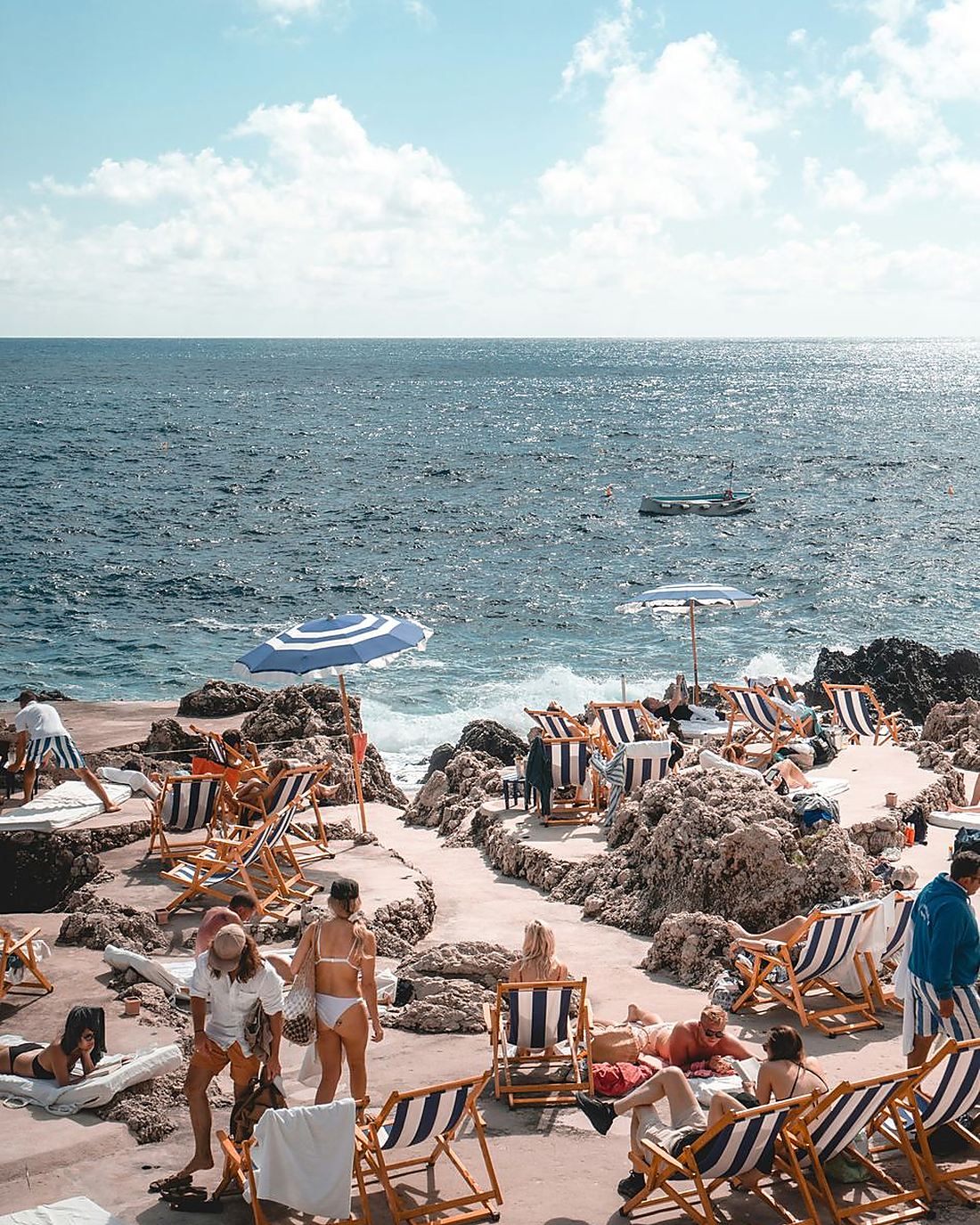 Badeklubb med stripete parasoller ved klippene på Capri